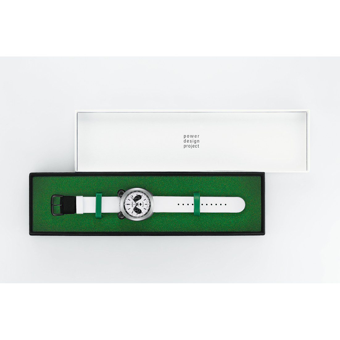 The Seiko Panda Chronograph HHK001 in its presentation box, a white sleeve marked power design project over a green tray